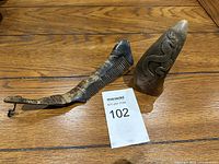 Front view of vintage buffalo horn comb with attached string loop and carved horn sculpture with dragon motif, placed on wooden surface.