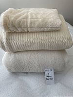 Stack of three cream blankets showing different textures: top fleece blanket, middle cotton waffle weave blanket, bottom fleece blanket