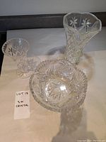 Three crystal pieces: two vases and one bowl, all with floral and geometric cut designs.