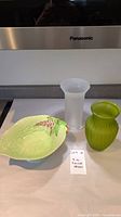 Overall view of the three pieces: a green Carlton Ware leaf dish, a white frosted vase, and a green ribbed glass vase