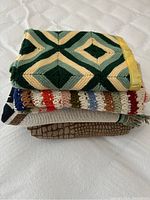 Stack of four blankets showing knitted pattern and brown blanket on bottom