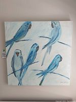 Front view of square canvas painting depicting five blue parakeets perched on branches with a light background.