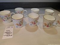 Eight Crown Trent china teacups arranged in two rows, showing floral patterns and gold trim on white china.