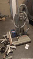 Electrolux vacuum cleaner with hose, wand, main floor head and various attachments arranged on floor.