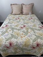 Full view of king size bed with floral coverlet and two striped pillows arranged at the head.