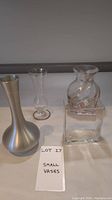 Four small vases - one pewter and three glass - arranged together with a note titled Small Vases