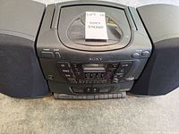 Front view of Sony stereo system with two attached speakers and top CD compartment visible.