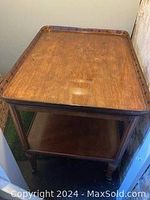 Full view of wooden bar cart showing overall structure, two shelves, turned legs and casters