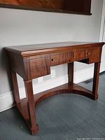 Front view showing overall desk structure with two drawers and curved stretcher base