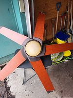 Full view of the wooden ceiling fan with five blades laid horizontally, showing its size and condition.