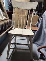 Photo of one white painted vintage wooden chair showing overall front and side profile including seat and decorative carved back.