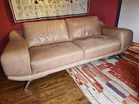Front view of the full sofa against a red wall showing overall condition and design