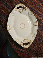 Top view of one white irregular octagonal Limoges bone china serving platter with gold trim and leaf accents, showing ornate pierced handles.