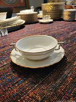 Fine bone china soup bowl with gold edging and scalloped edges, placed on cloth surface