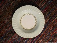 Top view of a fine bone china soup bowl showing fluted rim, green blush rim with gold edging and leaf pattern around white center