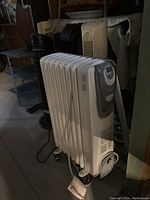 Full side view of white Kenwood oil heater showing fins and wheels at base.