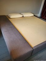 Side view of queen size bed frame showing beige base and wide soft grey fabric covered side piece