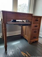 Solid wooden vintage writing desk shown from side angle with four drawers and pull-out keyboard tray