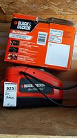 Black & Decker Air Station multi-purpose inflator in red and black with original product box placed behind it.