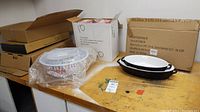 Melamine popcorn bowls, the 2-piece oval bakeware set boxed, and various other boxed bakeware and pans on a table