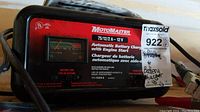 Front view of the MotoMaster battery charger showing meter, branding, model, and charging information.