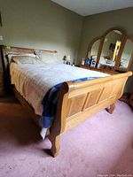 Full view of queen oak bed showing footboard, bed frame and bedding.