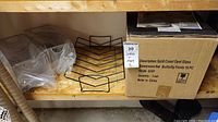 Storage shelf with two black wire baskets, packaged Gold Coast Opal Glass Butterfly Fields 16-piece dinnerware set box, and metal wire rack.