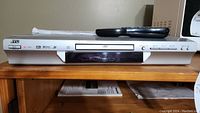 JVC XV-S302 DVD player silver front view with remote on top