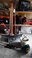 Full view of weed eater trimmer, two shovels, bucket with chemicals