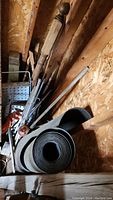 Assorted wooden spindles, roll of roofing paper and additional wood pieces in shed corner
