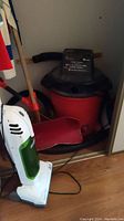 Photo showing the Sears Craftsman vacuum, snow shovel with wooden handle, and a small upright Eureka vacuum in a closet.