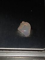 Polished opal stone placed on metallic surface showing fire colors