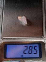 Polished white opal gemstone on digital scale showing weight 2.85 carats.