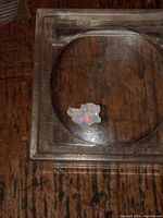 Raw fire opal specimen placed inside a clear display case showing multicolor play-of-color.