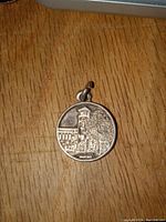 Photo of the front side of the sterling silver pendant showing a historic building with clock tower and tree.