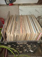 Top-down view of the crate filled with approximately 70 vintage LP records showing spine wear and aging.