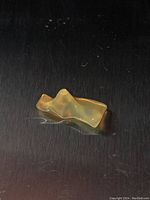 Yellow opal specimen on black background showing oblong shape and play of colors.