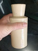 Hand held stoneware crock bottle showing cylindrical body shape with a wide neck opening.