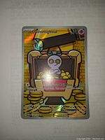 Front side of a full art Gimmighoul Pokémon card with gold and holo foil finish