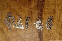 Five various sterling silver charms laid out on wooden surface