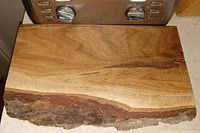 Top-down view of natural black oak slab with live edge, polished surface, and visible wood grain.