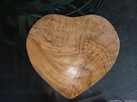 Top view of heart-shaped olive wood cutting board showing wood grain and smooth surface.