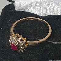 Ring angled view on black velvet surface, showing side profile, band, and flower cluster setting.