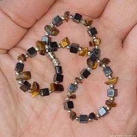 Close-up view of the Tigers Eye and Hematite anklet in a hand, showing the bead sizes, colors, and clasp detail.