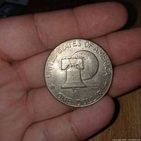 Reverse side of the coin showing the Liberty Bell superimposed on the Moon with inscriptions UNITED STATES OF AMERICA and ONE DOLLAR.