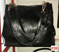 Front view of black leather Calvin Klein handbag with visible shoulder straps and gold hardware.