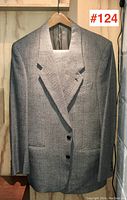 Full front view of the Giorgio Armani grey herringbone blazer hanging on a hanger.