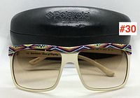 Front view of Juicy Couture sunglasses with Polaroid case in background