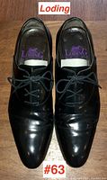 Pair of Loding men's black leather dress shoes on wooden floor, showing top view with laces tied and visible wear on leather.
