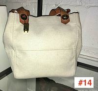 Front view of canvas exterior and leather straps with gold-tone hardware